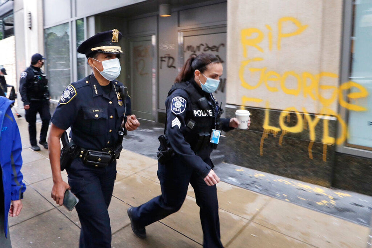 Seattle Police Chief Carmen Best (left) walks past graffiti, May 31, in downtown Seattle, following protests Saturday over the death of George Floyd who died after being restrained by Minneapolis police officers on May 25. (Elaine Thompson / Associated Press file photo)