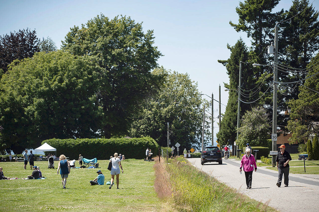 A ditch marks the Canada-U.S. border and separates people walking on the road (right) in Surrey, British Columbia, and those gathered at Peace Arch Historical State Park (left) in Blaine, Washington, on July 5. Although the B.C. government closed the Canadian side of the park in June due to concerns about crowding and COVID-19, people are still able to meet in the U.S. park due to a treaty signed in 1814 that allows citizens of Canada and the U.S. to unite in the park without technically crossing any border. (Darryl Dyck/The Canadian Press via AP)