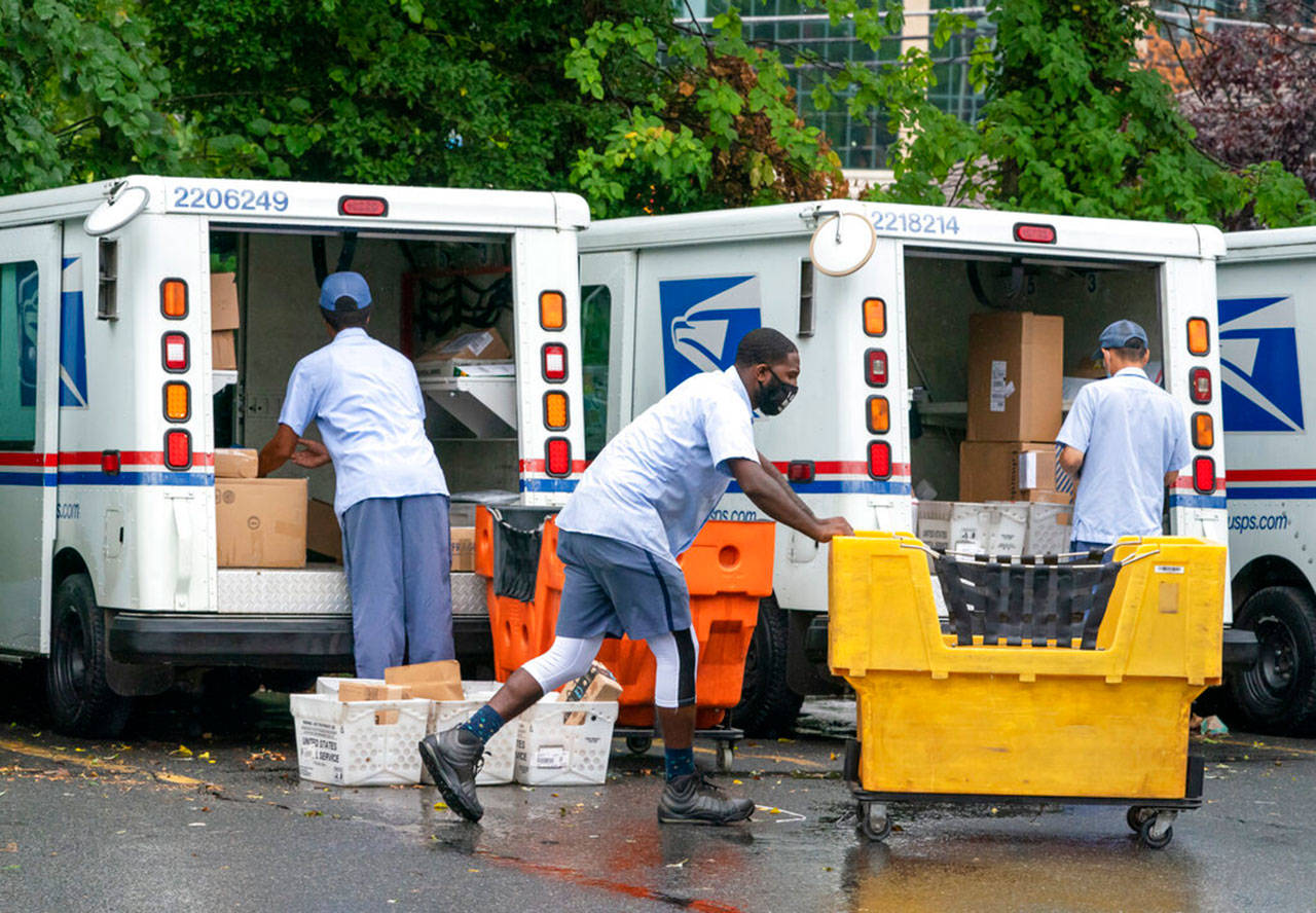 Carriers load mail trucks for deliveries at a U.S. Postal Service facility in McLean, Va., on July 31. The success of the 2020 presidential election could come down to a most unlikely government agency: the U.S. Postal Service. (J. Scott Applewhite / Associated Press)