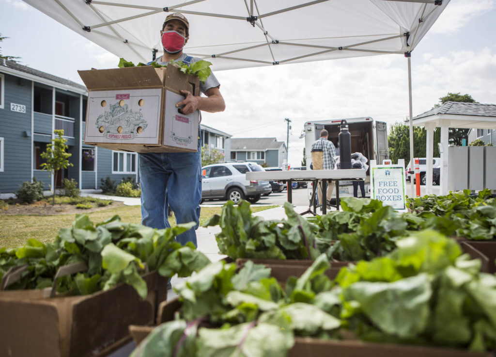 Vince Caruso of Caruso Farm in Snohomish delivers bags of his farm’s produce to Wiggums Park Place Apartments in Everett. (Olivia Vanni / The Herald)
