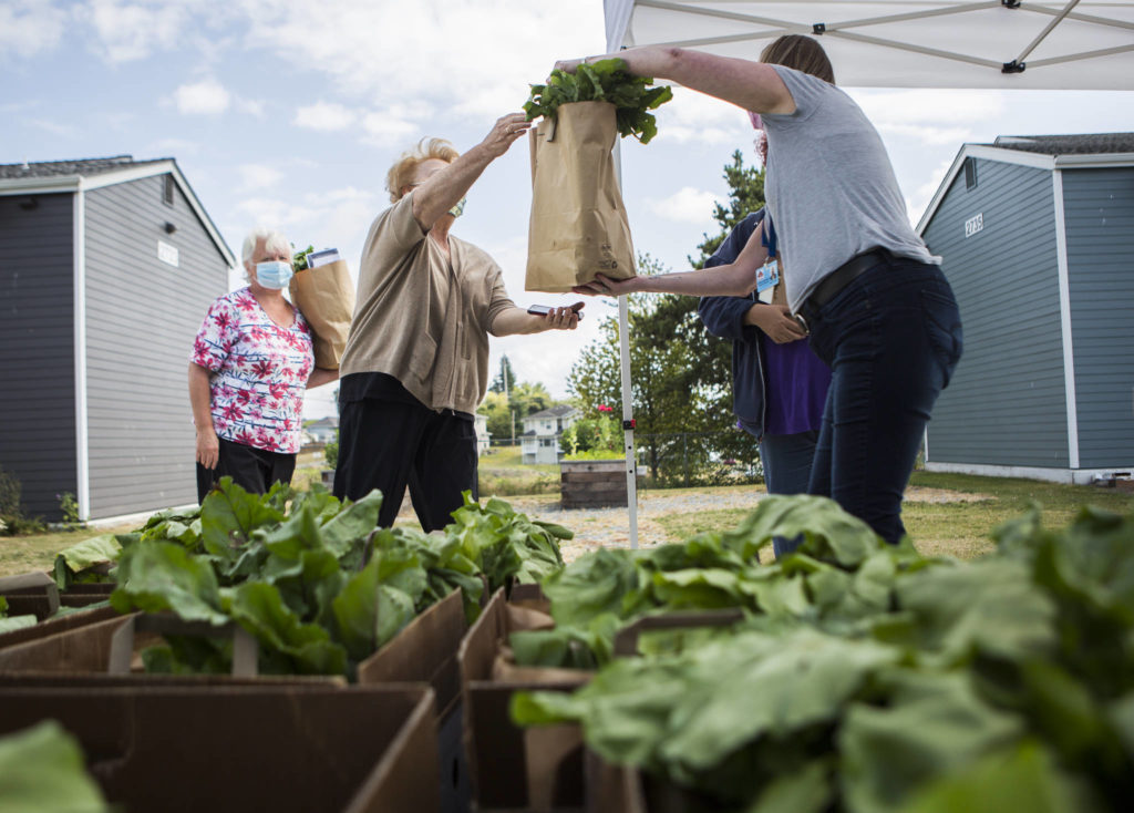 Everett Housing Authority family services manager Donelle Kienholz hands a bag of fresh produce to a resident. (Olivia Vanni / The Herald)
