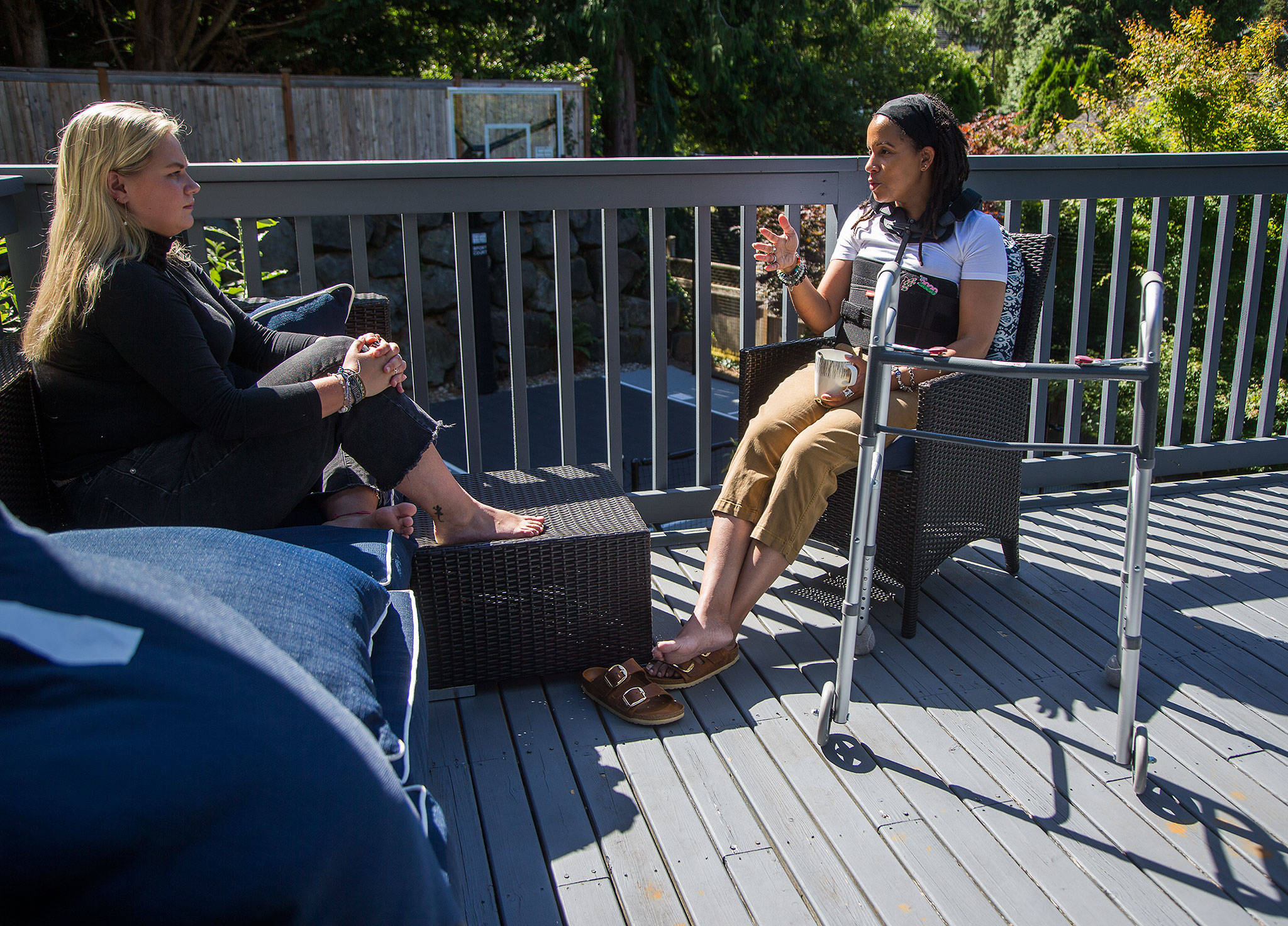 In a back brace and with her walker nearby, April Berg and her campaign manager, Katharine Gillen, chat Wednesday on the deck of Berg’s home in Mill Creek. Berg, a school board member and candidate for state office, suffered a broken back in an Election Day car crash. (Andy Bronson / The Herald)