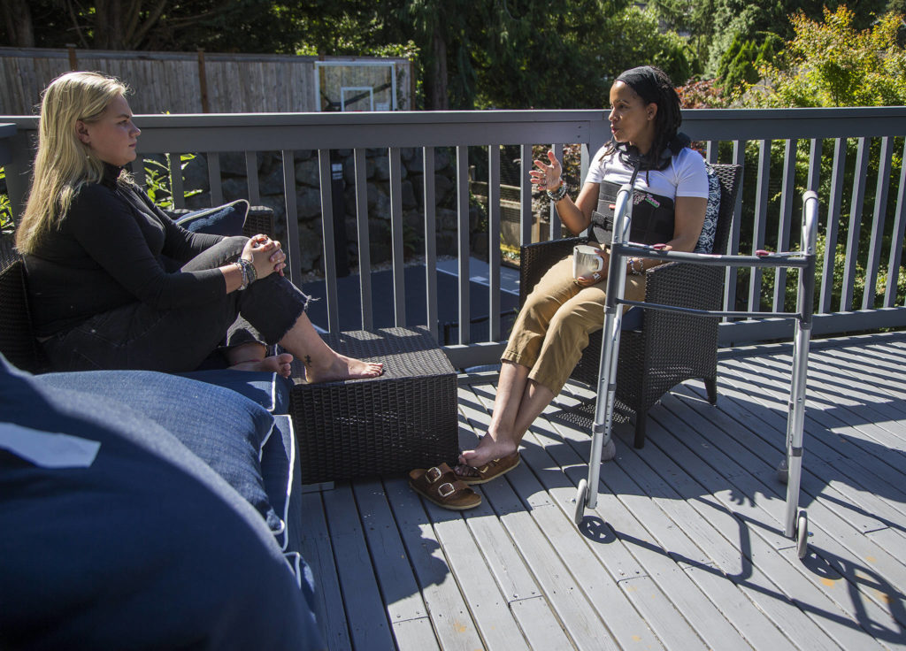 In a back brace and with her walker nearby, April Berg and her campaign manager, Katharine Gillen, chat Wednesday on the deck of Berg’s home in Mill Creek. Berg, a school board member and candidate for state office, suffered a broken back in an Election Day car crash. (Andy Bronson / The Herald)

