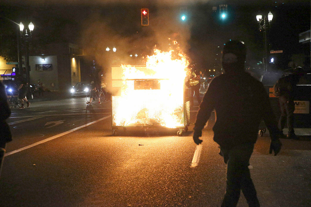 Some protesters in Portland, Oregon, lit a dumpster on fire and used it as a shield as they approached a precinct station, police said. (Associated Press)