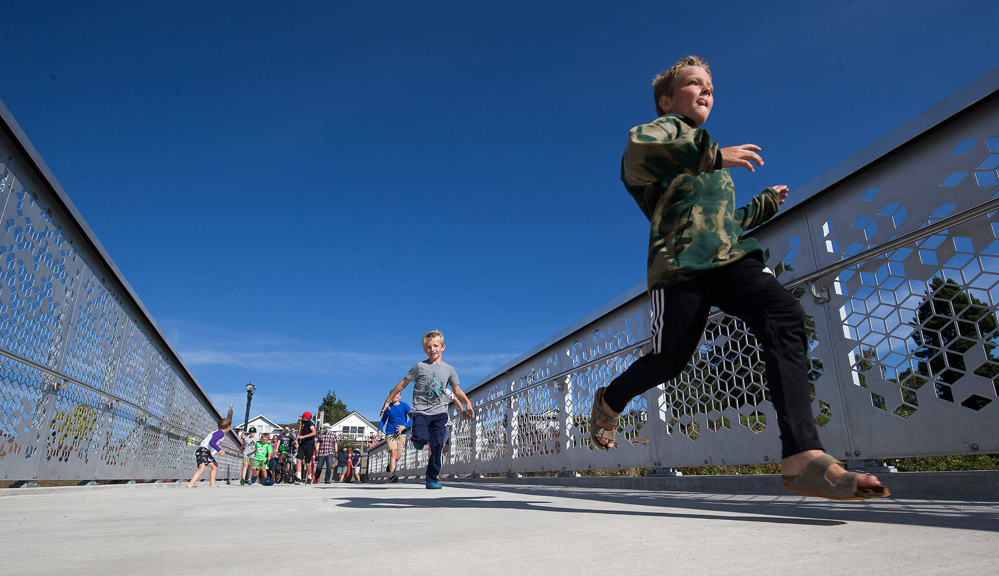 Kids race to see who can cross the Grand Avenue Park Bridge first as it opens for public use Wednesday in Everett. (Andy Bronson / The Herald)