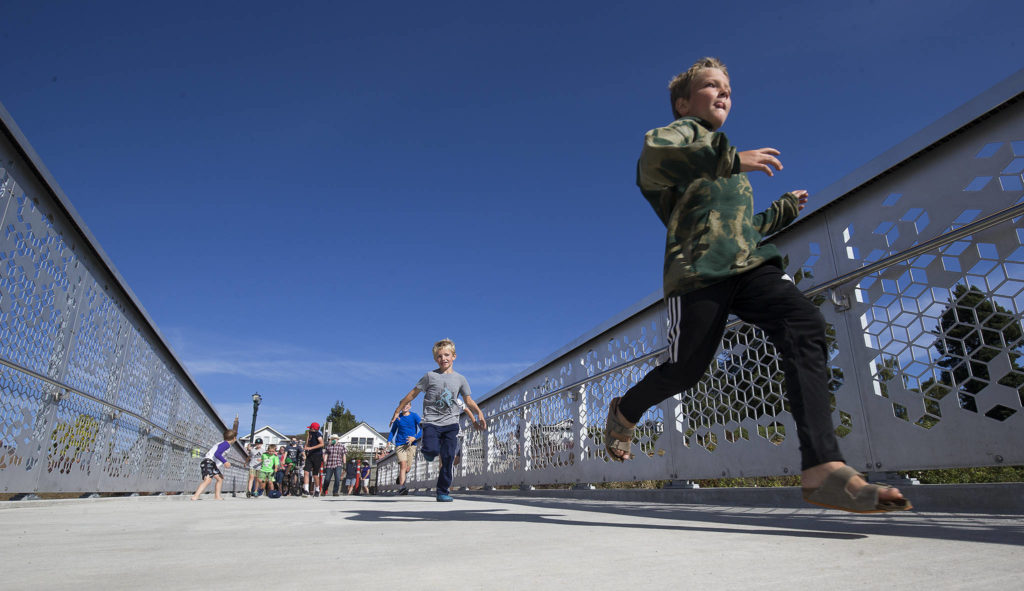 Kids race to see who can cross the Grand Avenue Park Bridge first as it opens for public use Wednesday in Everett. (Andy Bronson / The Herald)
