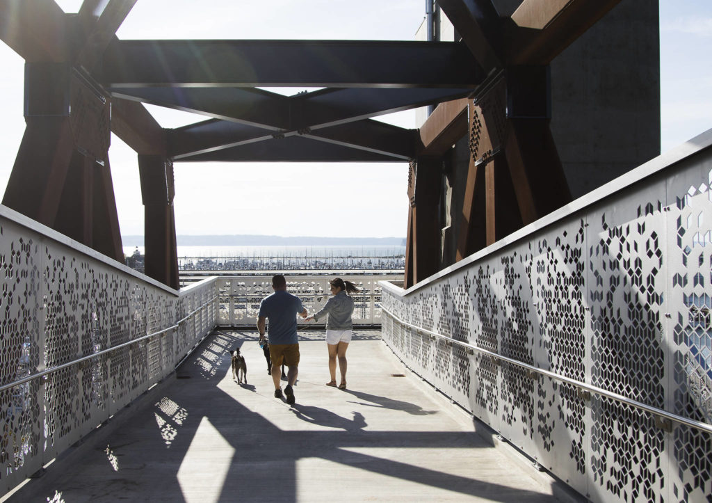 Devin and Taryn McLane appear to have the bridge to themselves as they walk dogs down the Grand Avenue Park Bridge after it opens for public use Wednesday in Everett. (Andy Bronson / The Herald)
