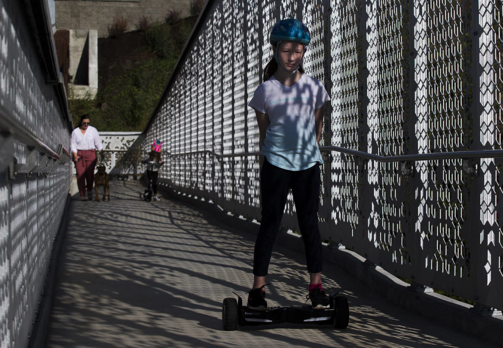 Averyn Radakovic rides her overboard up the ramp as the Grand Avenue Park Bridge opens for public use Wednesday in Everett. (Andy Bronson / The Herald)
