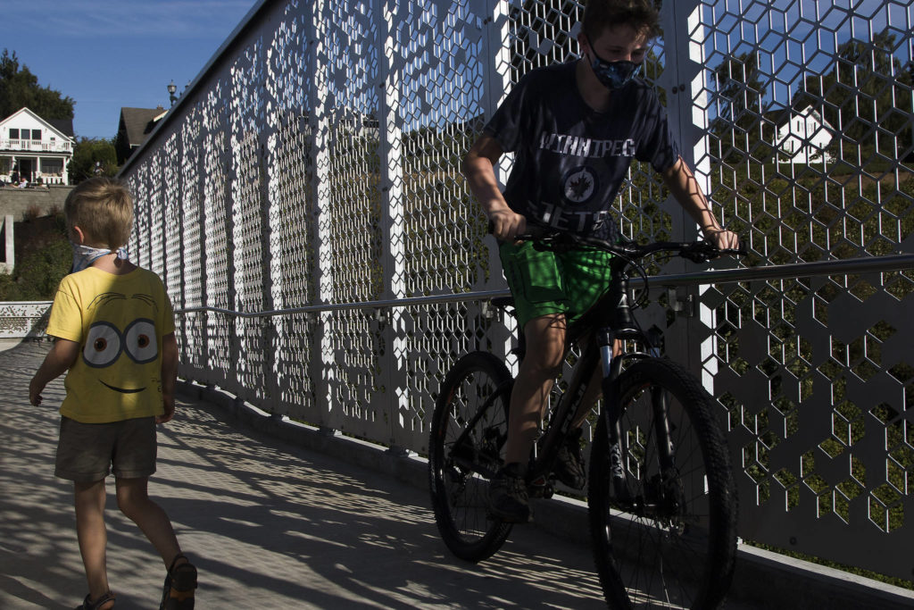 Walkers and riders pass by each other as they cross the Grand Avenue Park Bridge as it opens for public use Wednesday in Everett. (Andy Bronson / The Herald)
