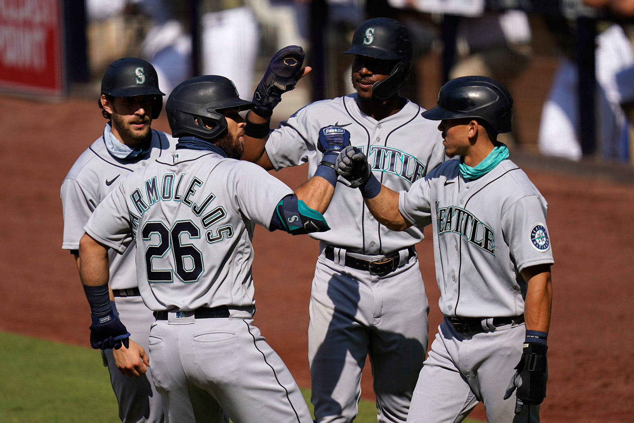 The Mariners’ Jose Marmolejos (26) is greeted by teammates Austin Nola (left), Kyle Lewis (second from right), and Sam Haggerty after hitting a grand slam during the first inning of a game against the Padres on Aug. 27, 2020, in San Diego. (AP Photo/Gregory Bull)