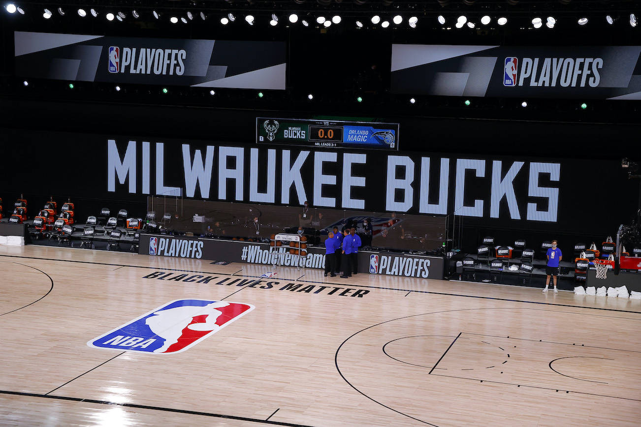 Referees huddle on an empty court at game time of a scheduled game between the Milwaukee Bucks and the Orlando Magic last Wednesday in Lake Buena Vista, Florida. The Bucks boycotted the game to protest the police shooting of Jacob Blake. (Kevin C. Cox/Getty Images/TNS)