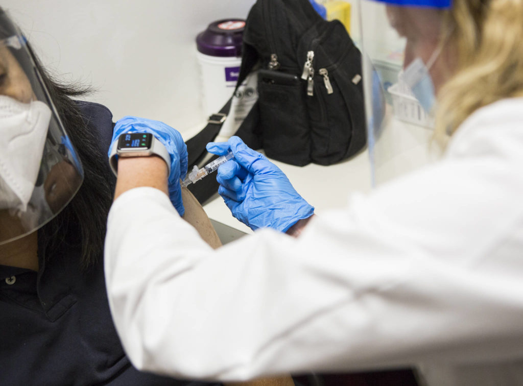QFC pharmacist Becky Buerhaus administers a flu shot on Wednesday in Everett. (Olivia Vanni / The Herald)
