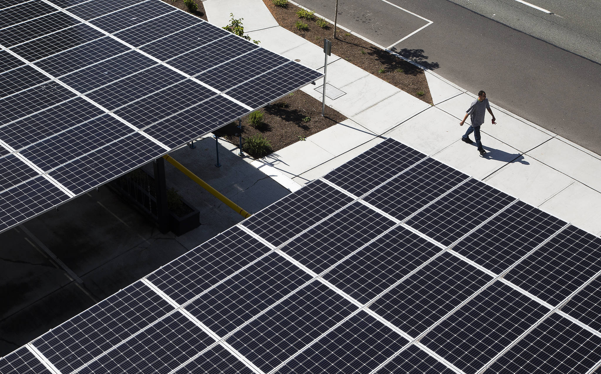 A man walks past the carport roof, which is covered with solar panels, at HopeWorks Station in Everett. The project has been awarded a Platinum LEED certificate for environmentally friendly design and features. (Andy Bronson / The Herald)