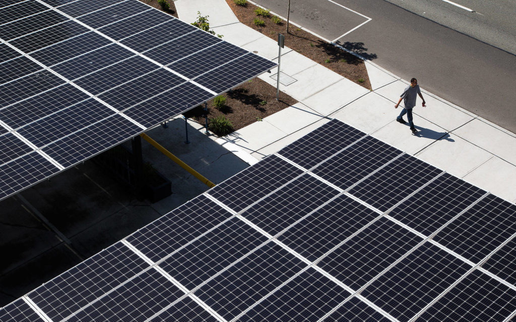 A man walks past the carport roof, which is covered with solar panels, at HopeWorks Station in Everett. The project has been awarded a Platinum LEED certificate for environmentally friendly design and features. (Andy Bronson / The Herald)
