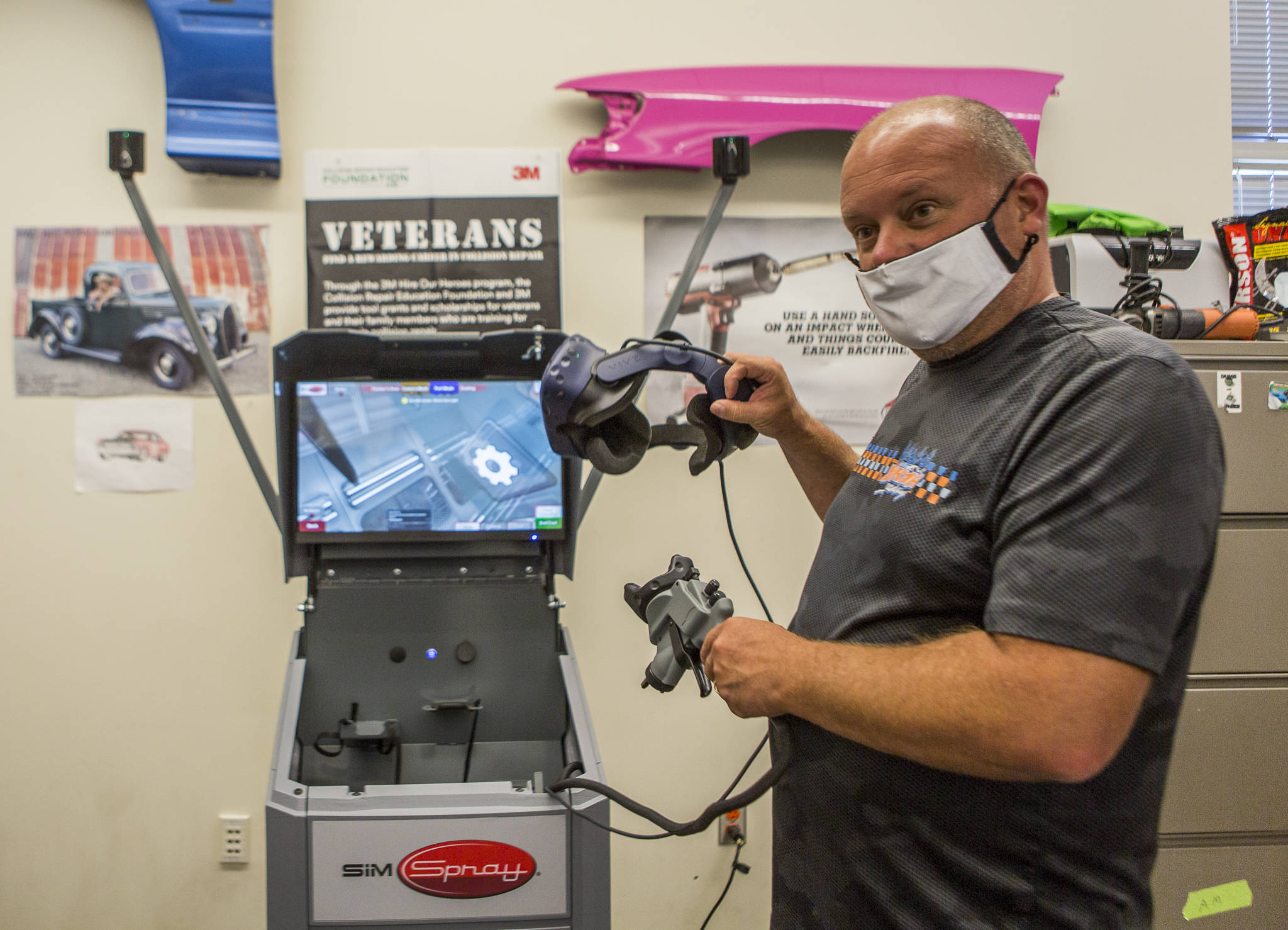 Sno-Isle Tech Skills Center auto body and collision repair teacher Shawn Fitzpatrick demonstrates how to use a VR headset students use for virtual car body painting. (Olivia Vanni / The Herald)