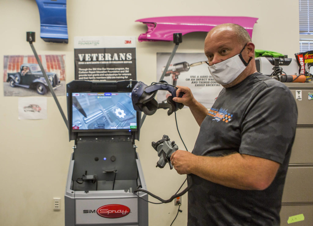 Sno-Isle Tech Skills Center auto body and collision repair teacher Shawn Fitzpatrick demonstrates how to use a VR headset students use for virtual car body painting. (Olivia Vanni / The Herald)
