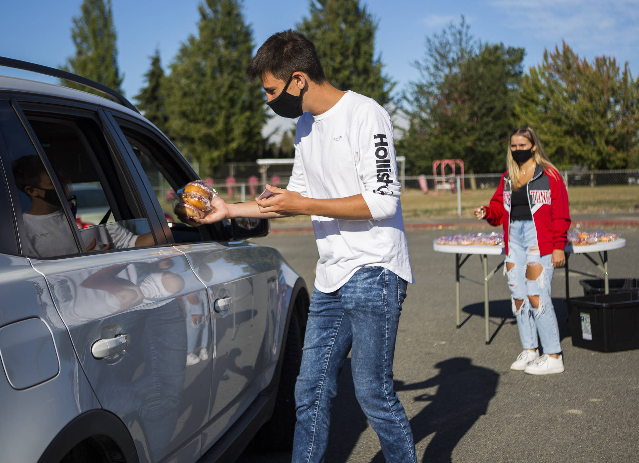 Stanwood High School student president Cody Vail hands out donuts to seniors Thursday morning. Senior class secretary and treasurer Shailee Polnasek stands in the background. (Olivia Vanni / The Herald)