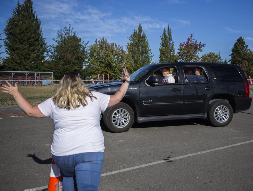 Stanwood High School English teacher Danielle Greenstreet waves and cheers at a car full of seniors Thursday morning. (Olivia Vanni / The Herald) 

