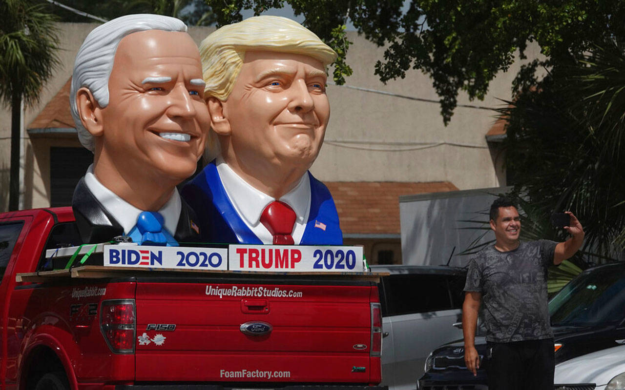 A passerby stops to take a selfie with foam sculptures of President Trump and Democratic presidential candidate former Vice President Joe Biden along Dixie Highway in Fort Lauderdale, Fla., Thursday, Sept. 3. (Joe Cavaretta / South Florida Sun-Sentinel)
