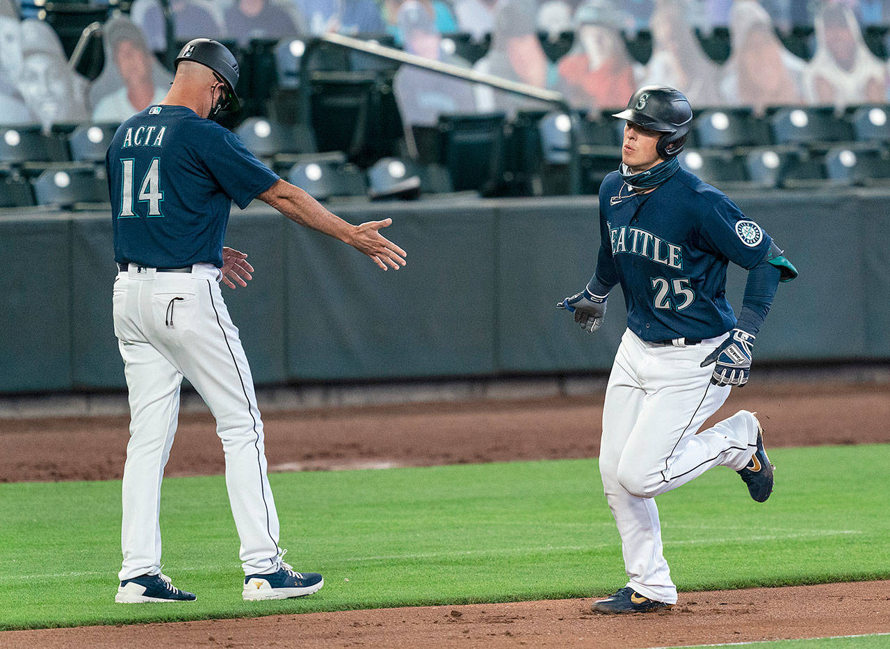 The Seattle Mariners’ Dylan Moore is congratulated by third base coach Manny Acta after hitting a solo home run off Texas Rangers starting pitcher Kolby Allard during the third inning Monday in Seattle. (Stephen Brashear / Associated Press)