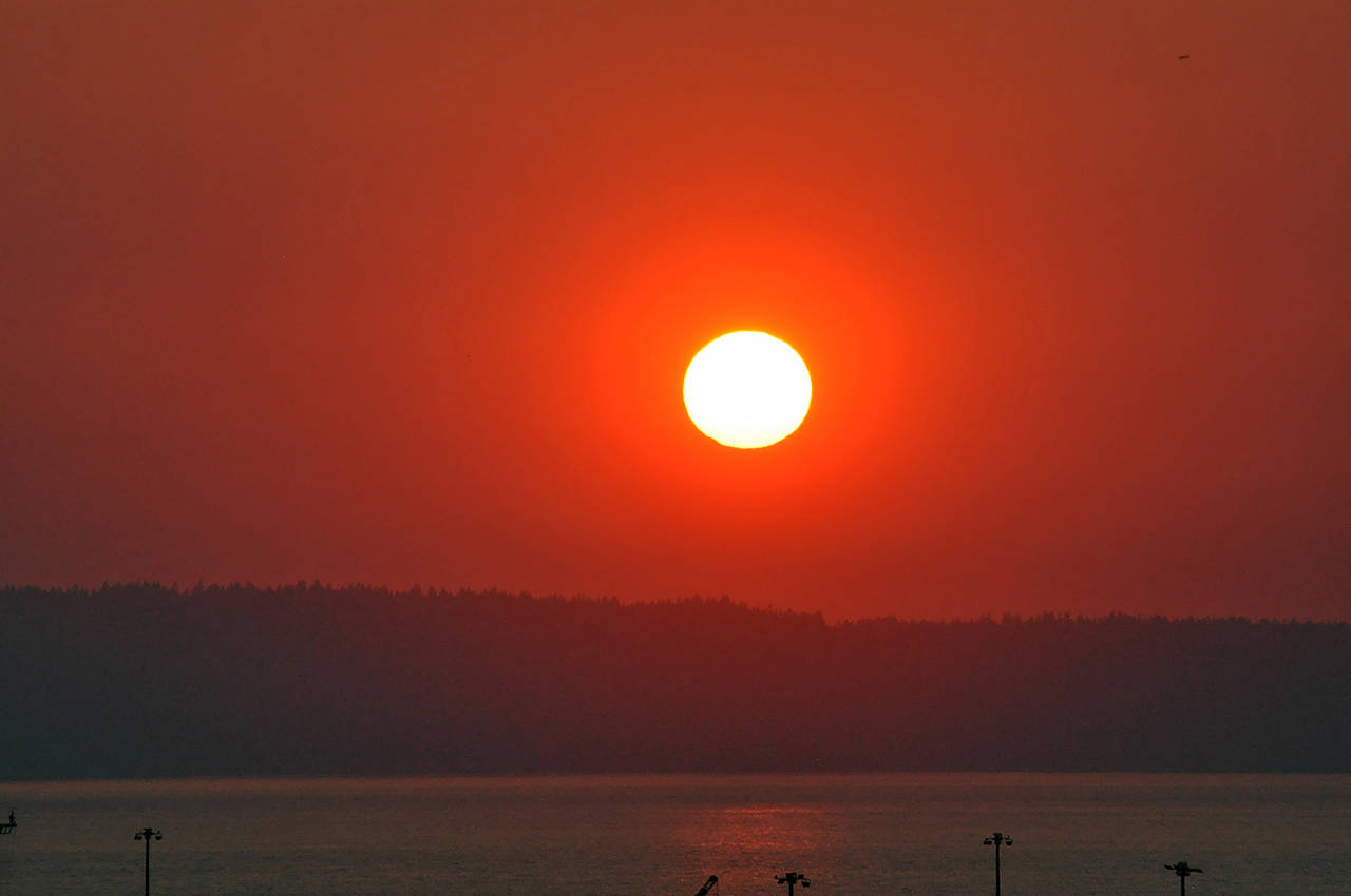 The sun turned the sky a glowing red before disappearing into the smokey haze Tuesday evening in this view looking west toward Whidbey Island from north Everett. (Sue Misao / The Herald)