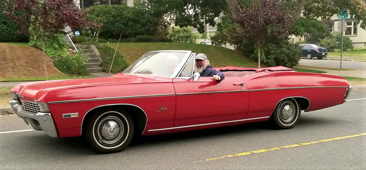 Everett’s Jack O’Donnell pauses to greet a bystander as he drives up Rucker Avenue during Saturday’s informal cruise. (Julie Muhlstein / The Herald)