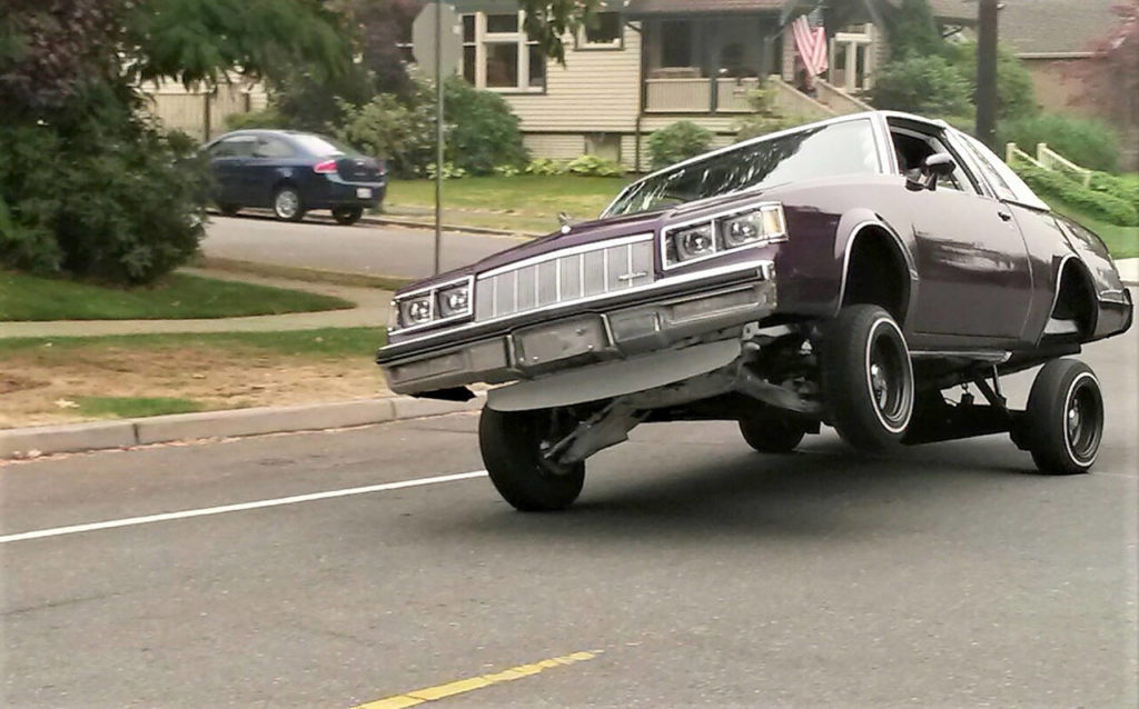 Up on two wheels, a car equipped with custom lifts wows bystanders during Saturday’s informal cruise in north Everett. (Julie Muhlstein / The Herald)
