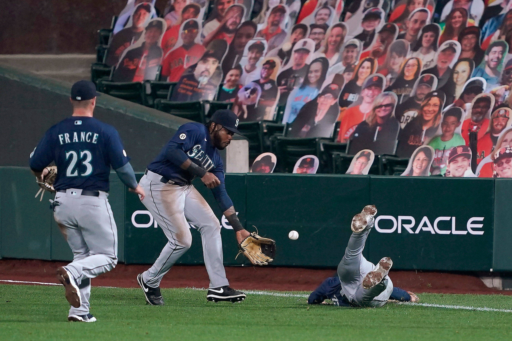 Mariners first baseman Evan White (right) dives for but can’t make the catch on a double by the Giants’ Wilmer Flores, as right fielder Phillip Ervin (center) and second baseman Ty France (23) come to assist during the fourth inning of a game Sept. 9, 2020, in San Francisco. (AP Photo/Tony Avelar)