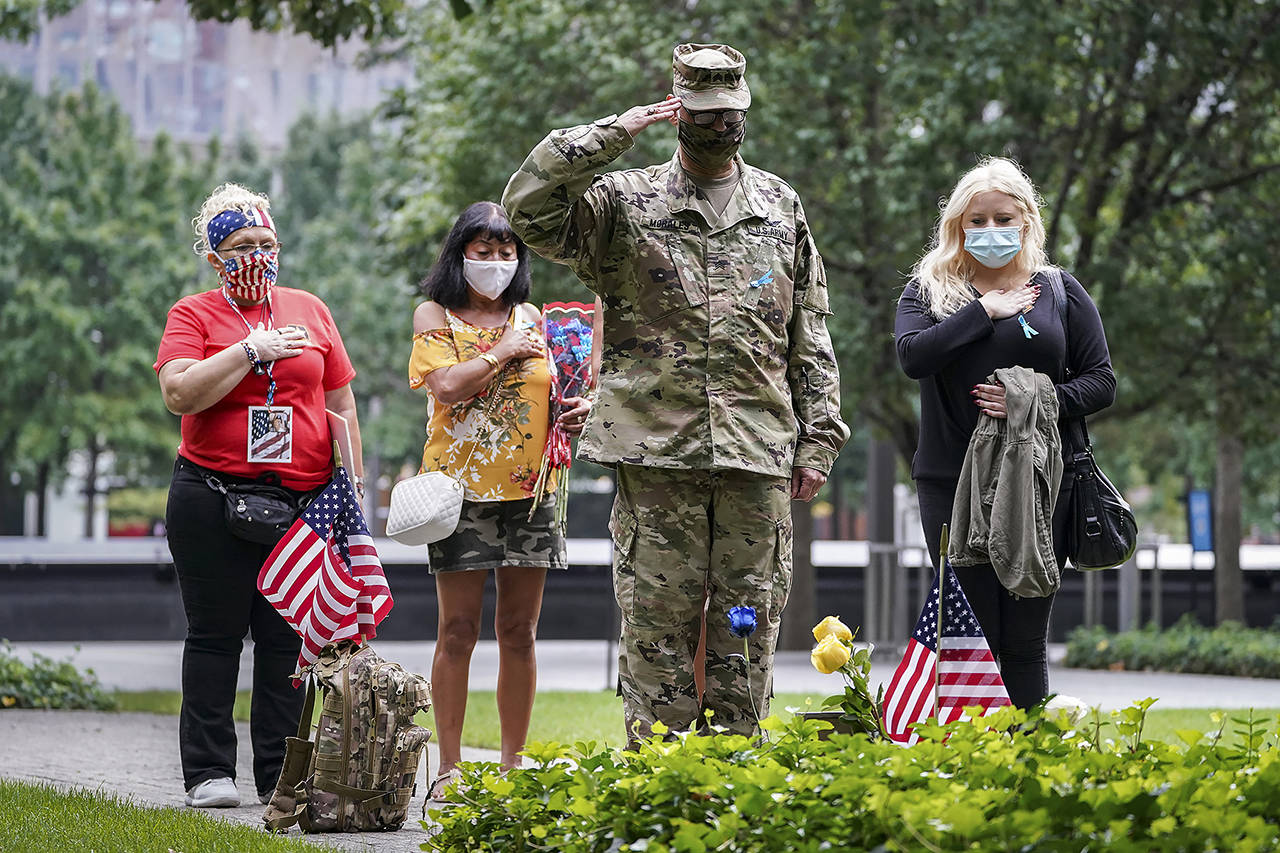 U.S. Army Sgt. Edwin Morales (center right) salutes after placing flowers for fallen FDNY firefighter Ruben D. Correa at the National September 11 Memorial and Museum on Friday in New York. (AP Photo/John Minchillo)