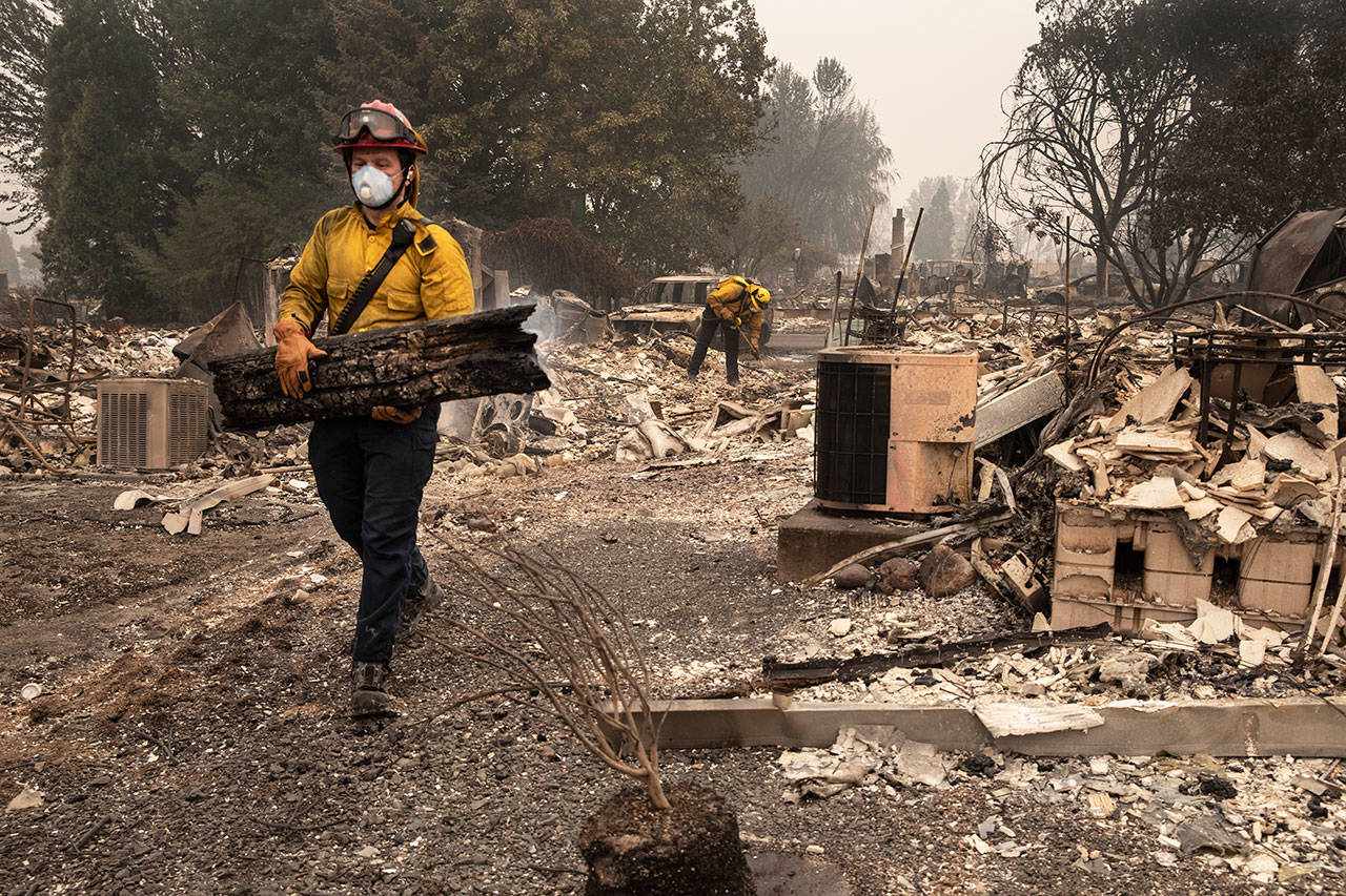 Jackson County District 5 firefighter Captain Aaron Bustard works on a smoldering fire in a burned neighborhood in Talent, Ore., Friday, Sept. 11, 2020, as destructive wildfires devastate the region. (AP Photo/Paula Bronstein)