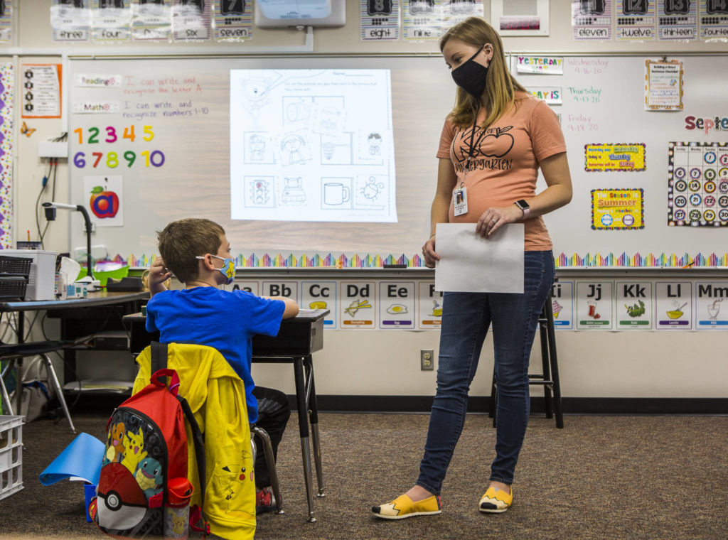 Kindergarten teacher Kari Richards answers a question from one of her three masked and socially distanced students during class at Twin City Elementary School on Thursday in Stanwood. (Olivia Vanni / The Herald)
