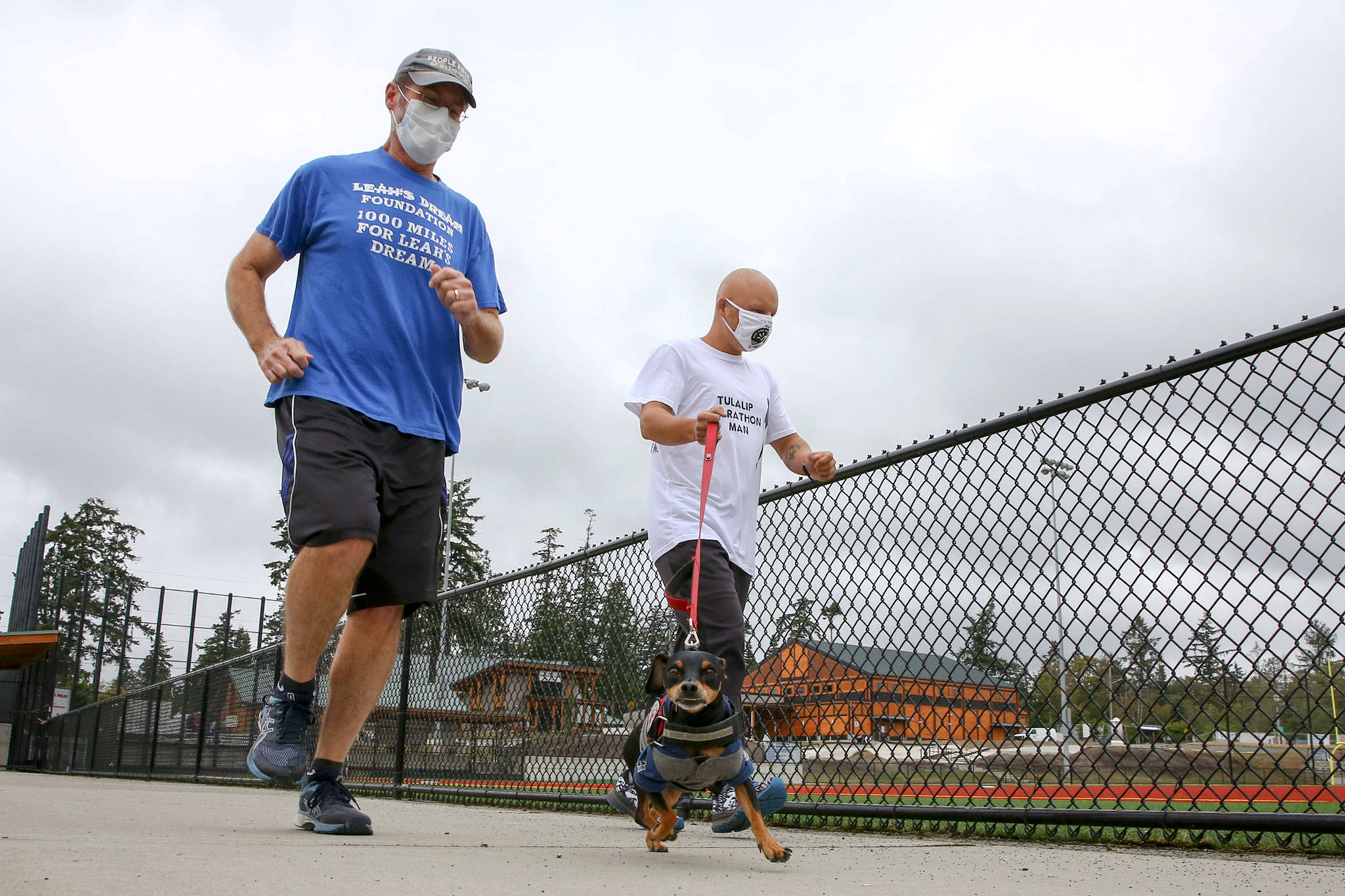 Jim Strickland (left) runs with Tyler Fryberg for the final mile in a 1,000-mile challenge to raise money for Leah’s Dream Foundation. (Kevin Clark / The Herald)