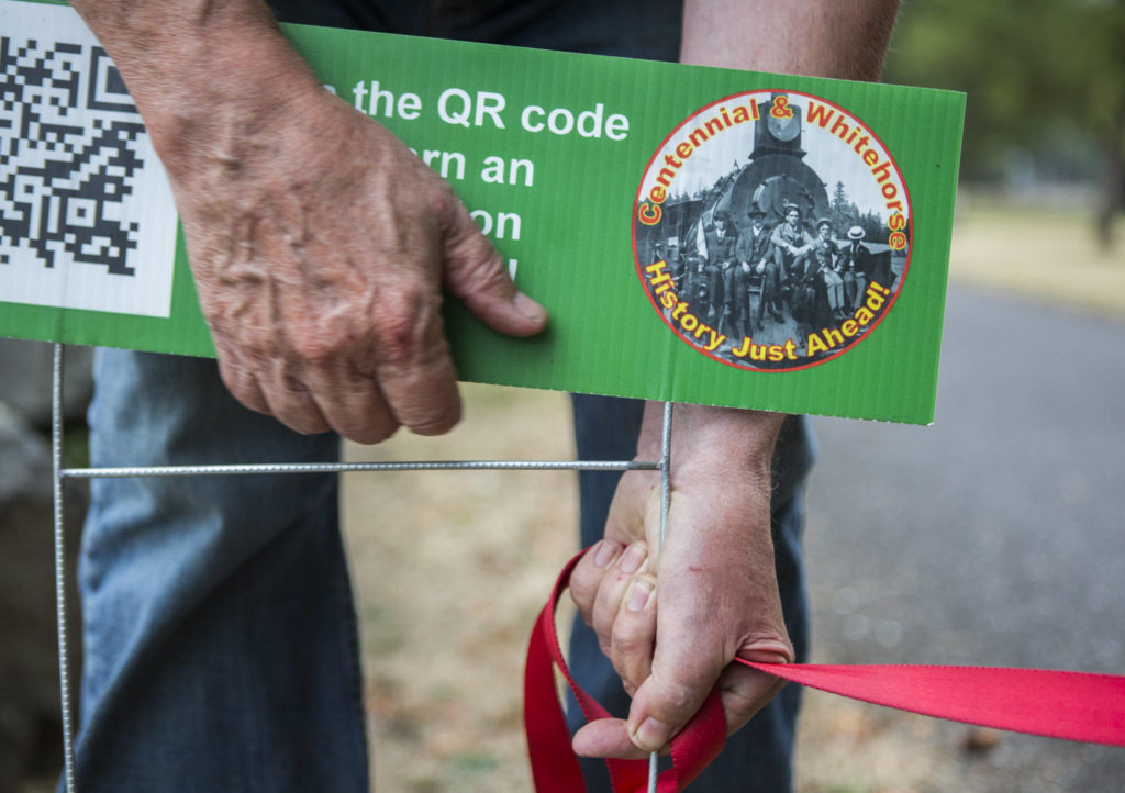 Fred Cruger adjusts one of the QR code signs that make up the history walk on Sept. 18. (Olivia Vanni / The Herald)
