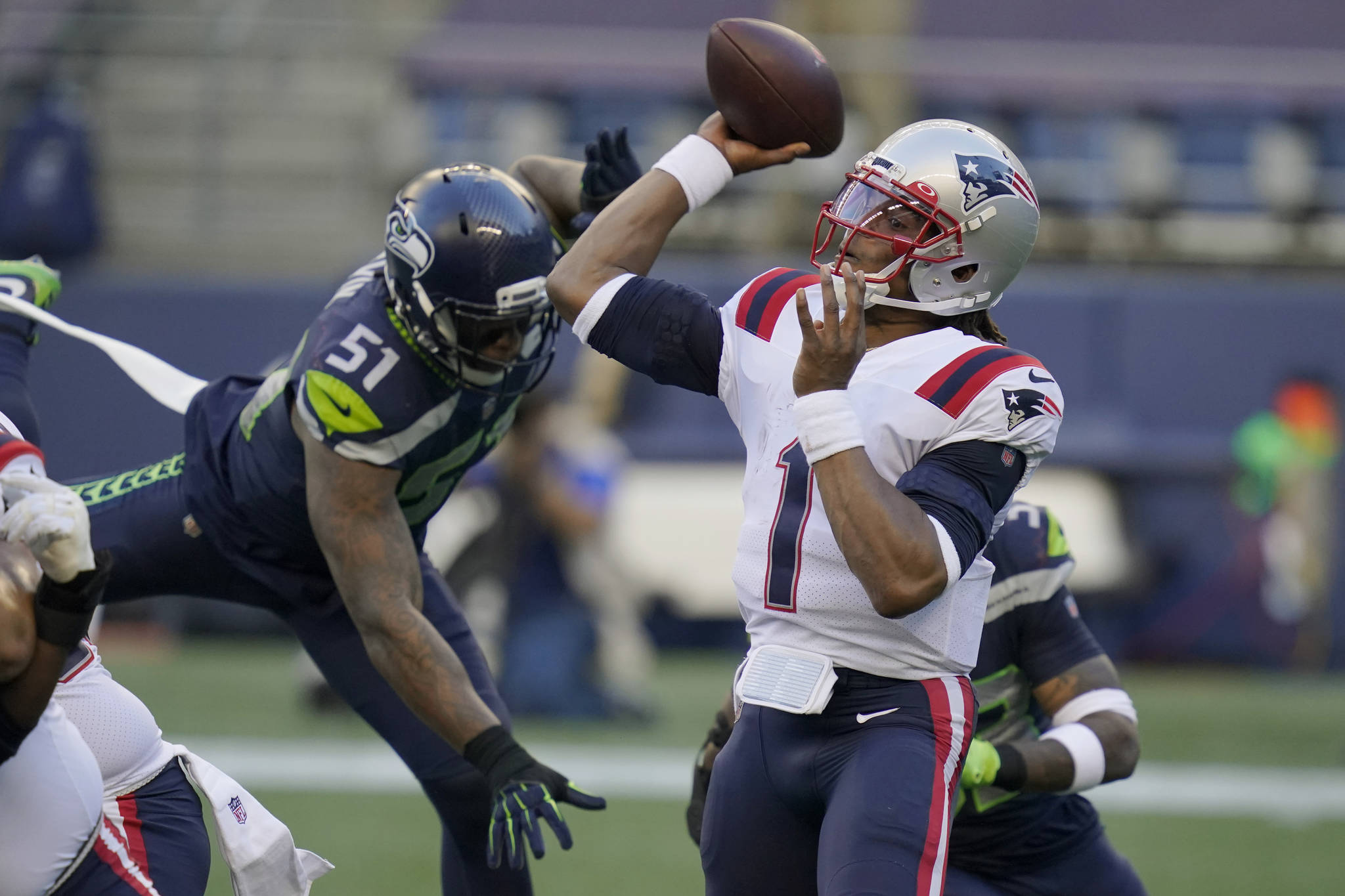 New England Patriots quarterback Cam Newton (1) passes as Seattle Seahawks linebacker Bruce Irvin (51) closes in during the first half of their game Sunday at CenturyLink Field. (AP Photo/Elaine Thompson)