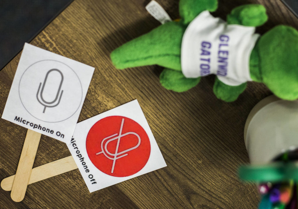 Adams raises these signs to ask students to use their microphones while teaching through online video. (Olivia Vanni / The Herald)
