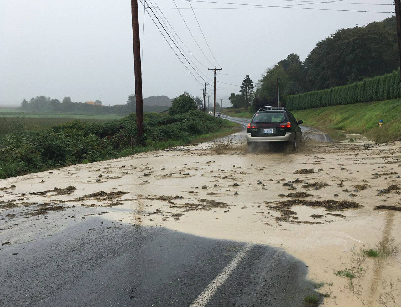 A car drives down Lowell Larimer Road south of Snohomish after a mudslide on Friday afternoon. (Photo courtesy of Barbara Carlson)