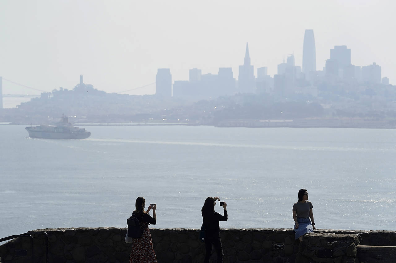 People take pictures at a vista point with the San Francisco skyline obscured by smoke from wildfires and heat in the background Monday near Sausalito, California. (AP Photo/Eric Risberg)