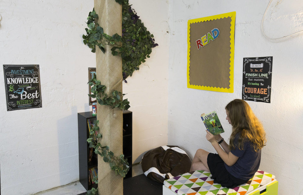In a warehouse area turned classroom, Nathalie Sandberg finds a corner to read at Malicious Women Co. in Snohomish. (Andy Bronson / The Herald)
