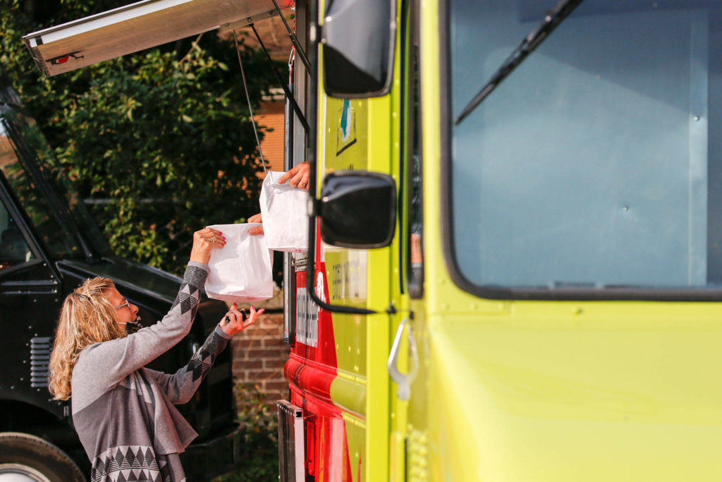 Caroline Petry collects her order at one of the food trucks parked at Beverly Boulevard and Madison Street in Everett on Oct. 1. (Kevin Clark / The Herald)
