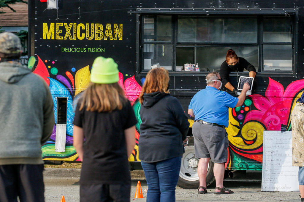 People gather in a parking lot to sample food truck offerings on Beverly Blvd. in Everett on Oct. 1. (Kevin Clark / The Herald)

