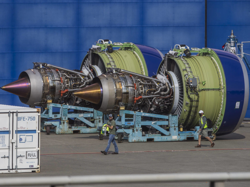 Boeing workers walk past two airplane engines during a shift change on Thursday in Everett. (Olivia Vanni / The Herald)
