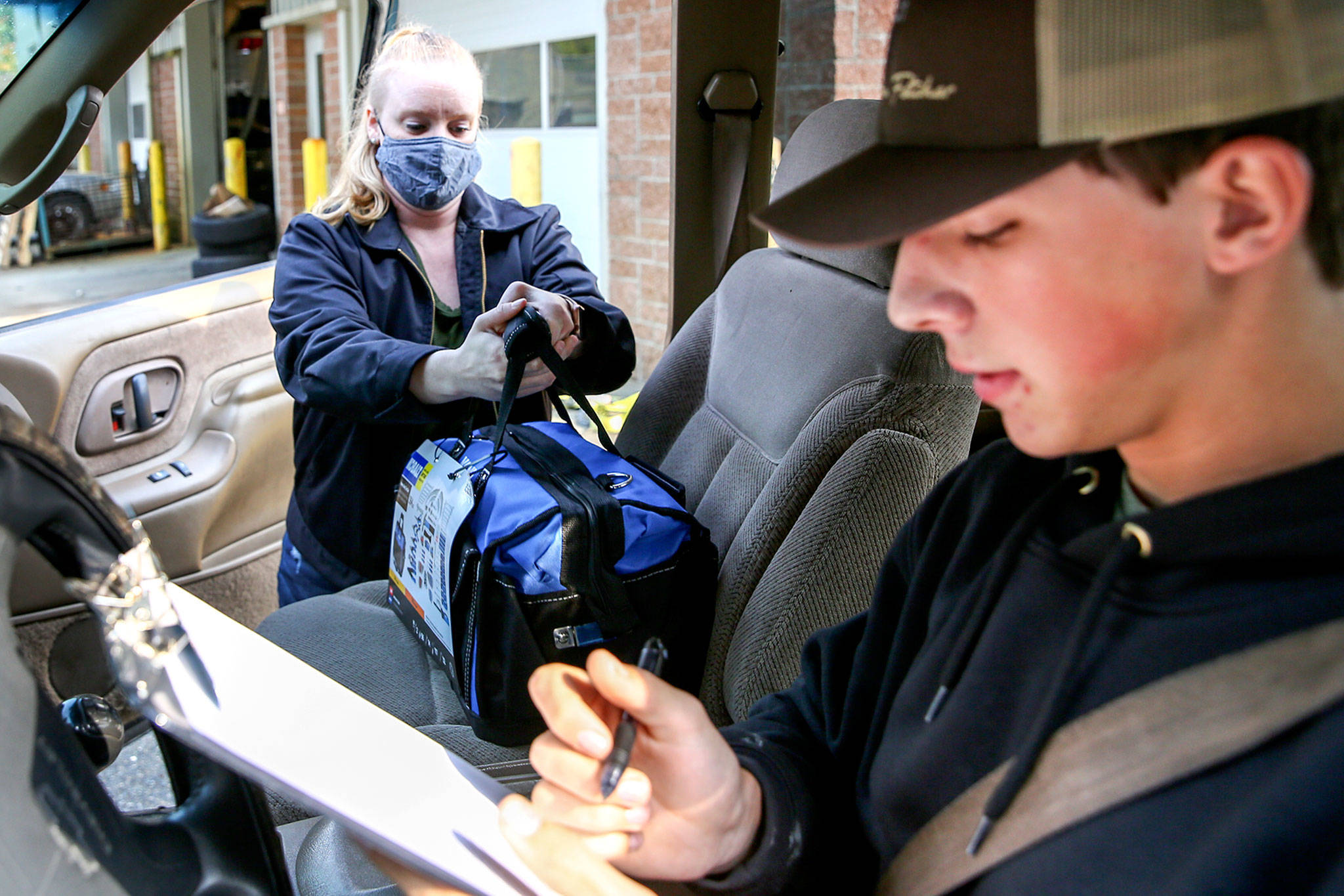 Kellie Shanahan loads Jacob McGovern’s vehicle with his class tool bag at Meadowdale High School in Lynnwood on Oct. 1, 2020. (Kevin Clark / The Herald)