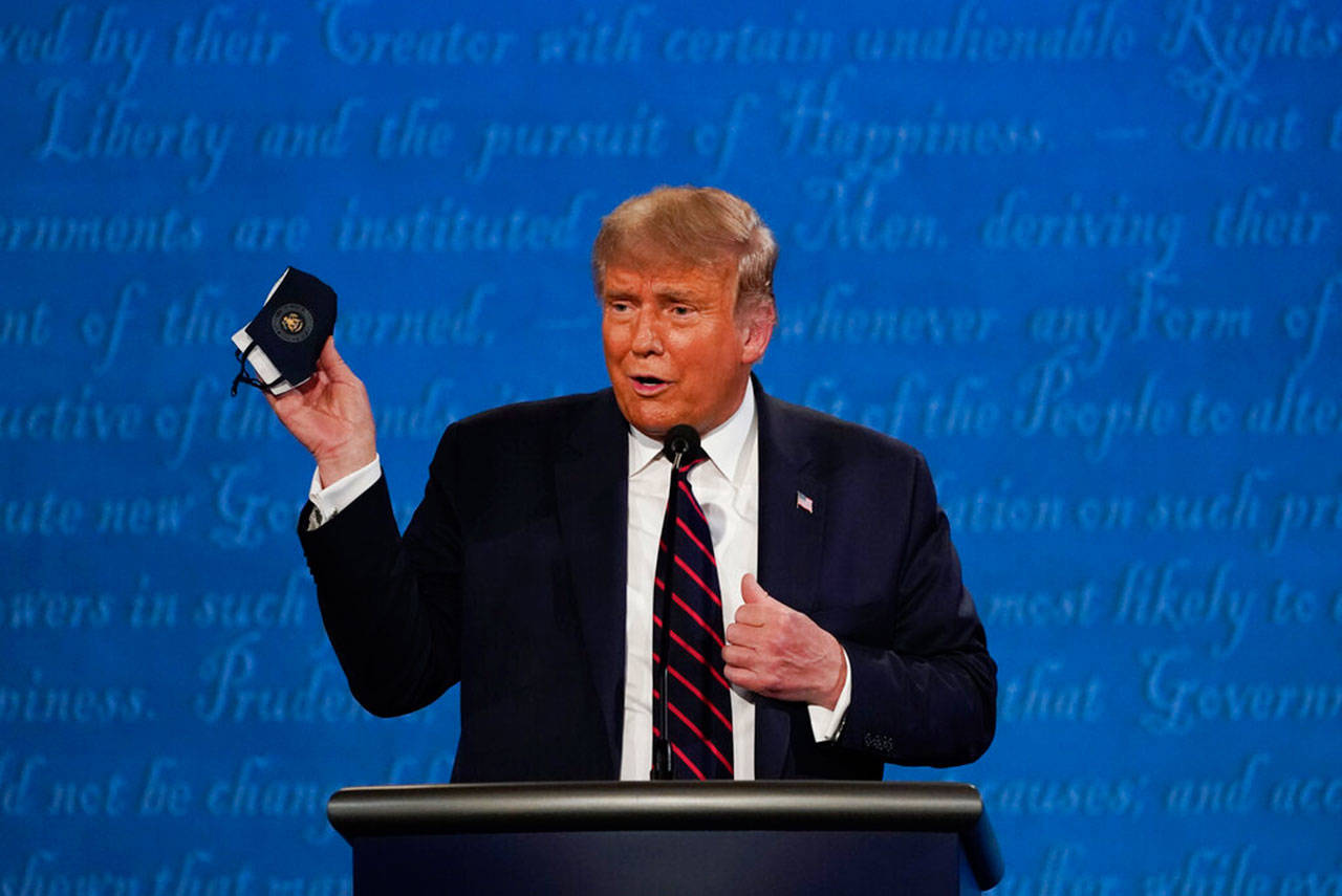 President Trump holds up his facemask during the first presidential debate at Case Western University and Cleveland Clinic, in Cleveland, Ohio, on Tuesday. President Trump and first lady Melania Trump have tested positive for the coronavirus, the president tweeted early Friday. (Julio Cortez / Associated Press file)