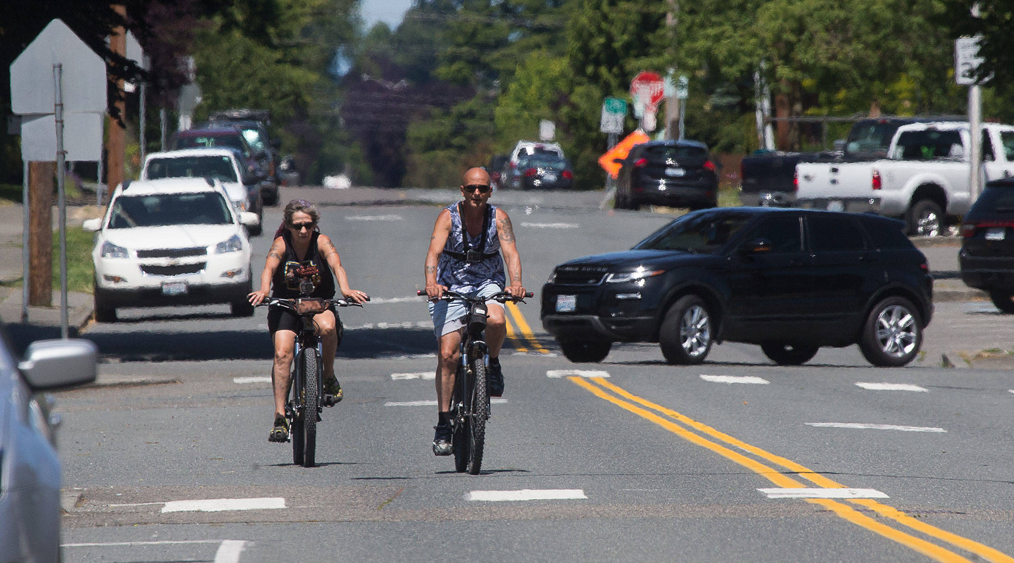 Two people ride bikes July 15 along traffic on Hoyt Avenue in Everett. The city closed parts of Hoyt and three other roads to most vehicle traffic for its Healthy Streets program, but ended the active transportation initiative Oct. 5. (Andy Bronson / The Herald)