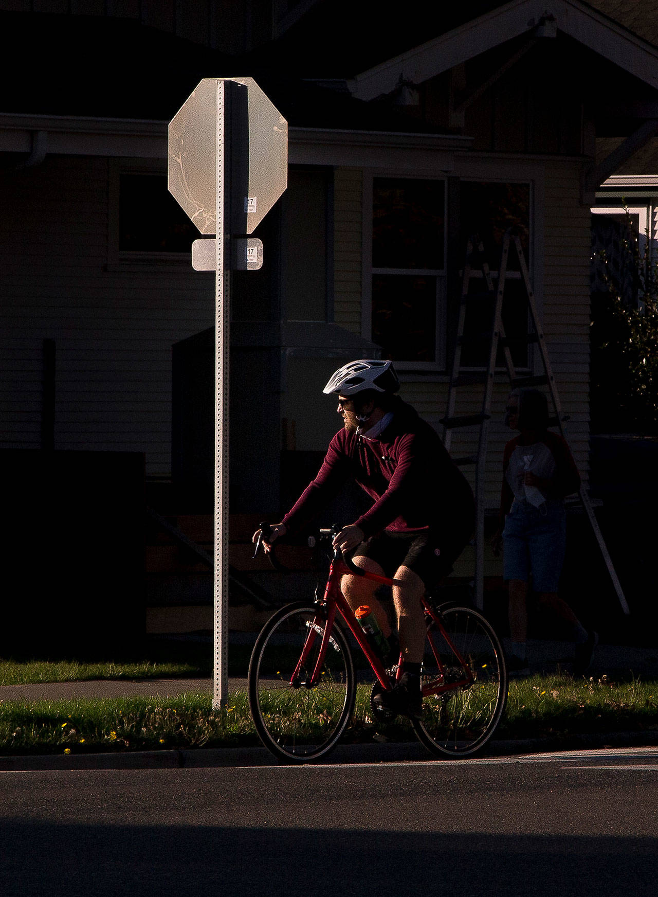 A biker looks right and slowly proceeds through a stop sign at 16th Street and Colby Avenue on in Everett. As of Oct. 1, bike riders can treat stop signs like yield signs. (Andy Bronson / The Herald)