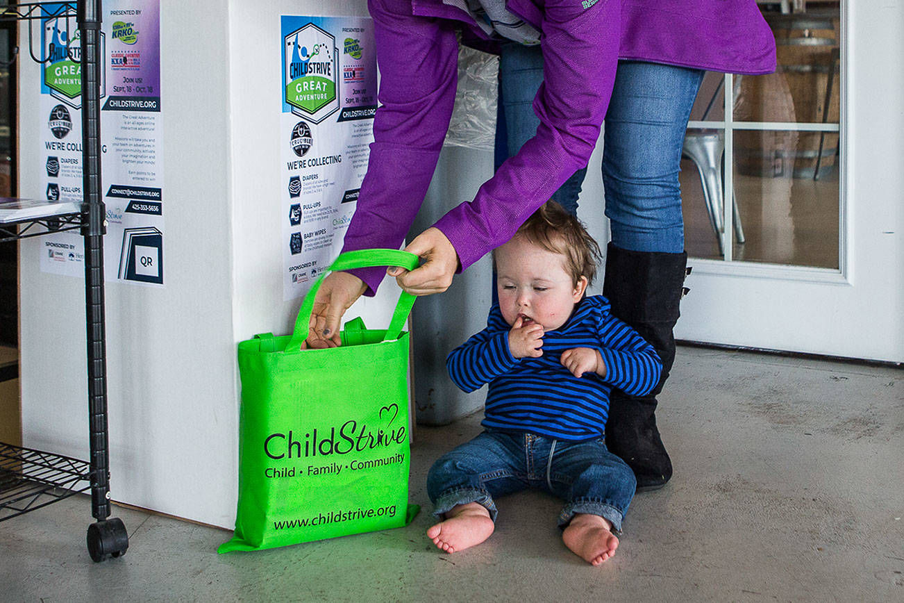 Whitney Stohr and her son Malachi Stohr-Hendrickson, 2, add diapers to a ChildStrive donation box on Oct. 7 at Crucible Brewing in Everett. Malachi receives early intervention services through ChildStrive. (Olivia Vanni / The Herald)