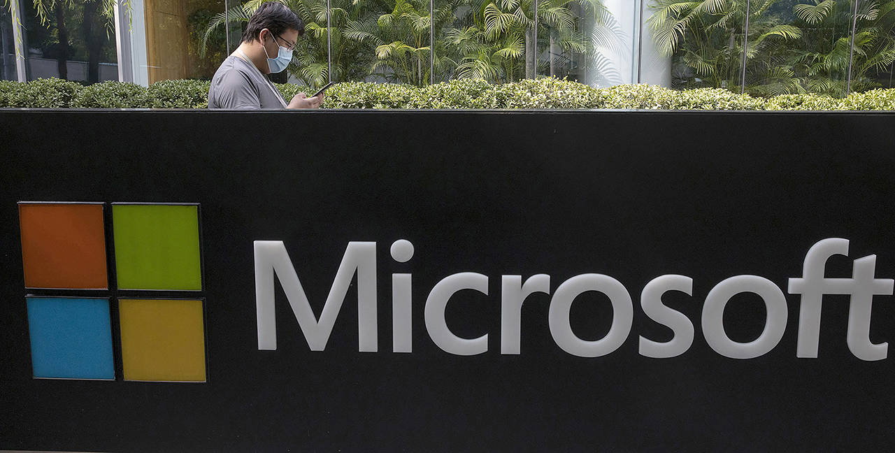 A man looks at this phone outside the Microsoft office in Beijing, China. (AP Photo/Ng Han Guan, File)