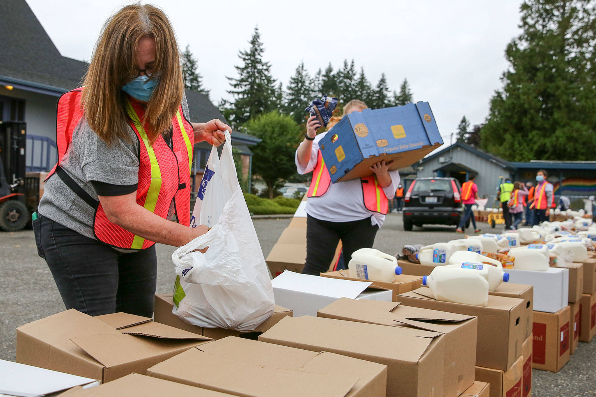 Lisa Naasz (left) and Lesli Gisvold load boxes for distribution Friday morning at the Faith Food Bank at Faith Lutheran Church in Everett on October 9, 2020. (Kevin Clark / The Herald)