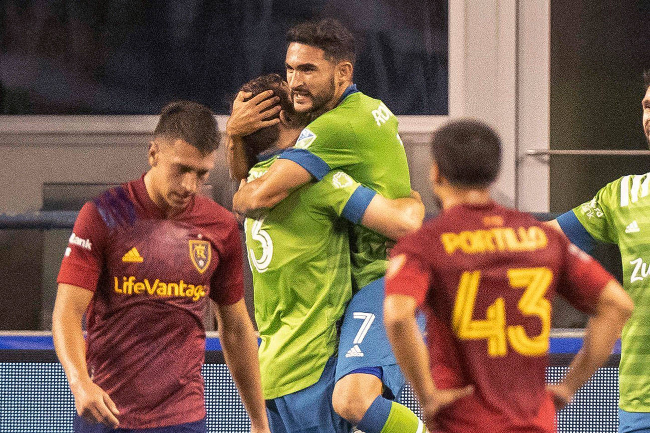 Seattle Sounders' Cristian Roldan hops into the arms of Jordan Morris who scored against Real Salt Lake during the first half of an MLS soccer match Wednesday, Oct. 7, 2020, in Seattle. (Dean Rutz/The Seattle Times via AP)