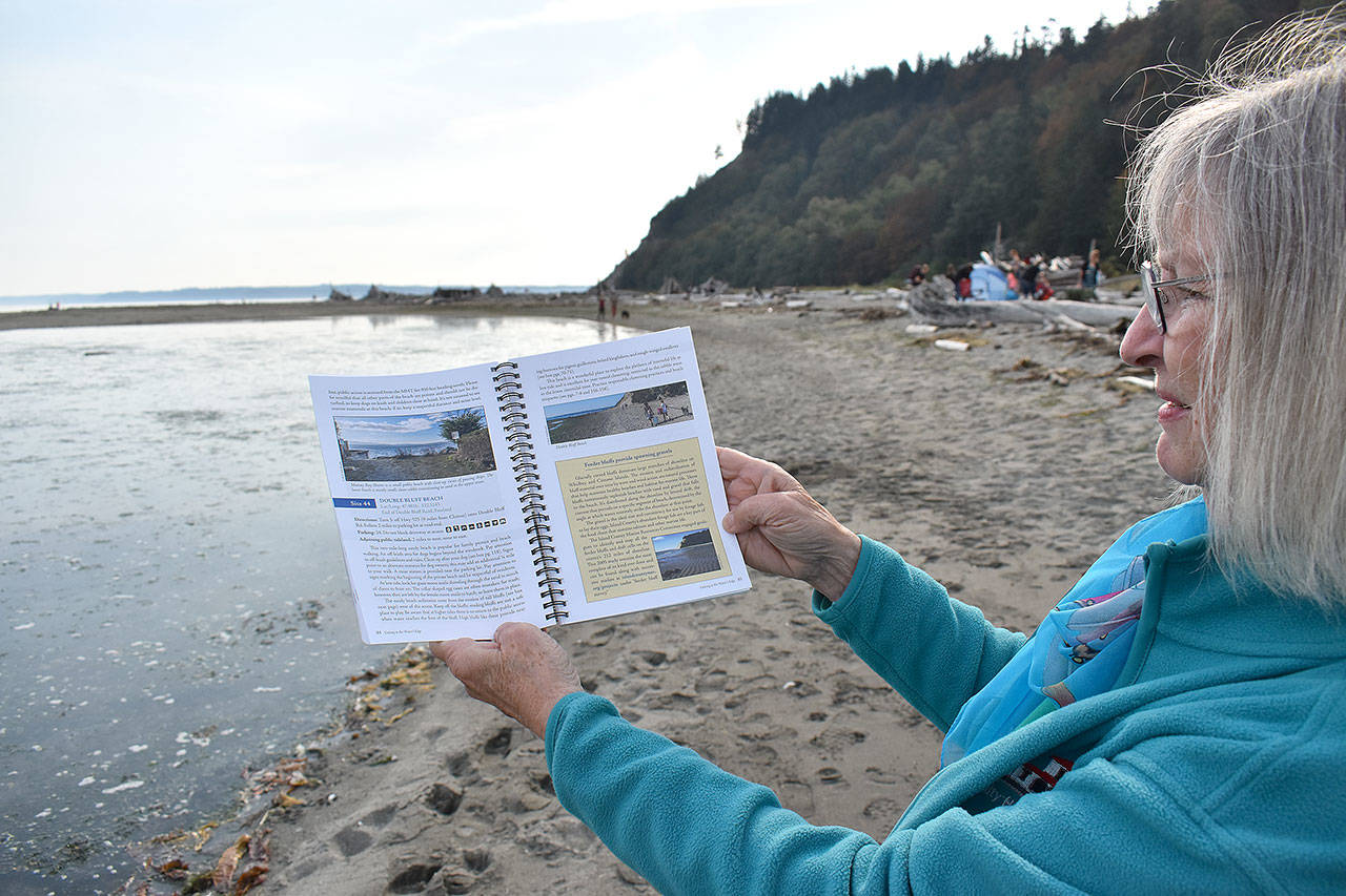 Jeanie McElwain holds the new edition of “Getting to the Water’s Edge,” a book that includes information about beach accessibility, fishing spots, natural history, species identification and more, including all of the sea creatures that can be found at Double Bluff in South Whidbey. (Emily Gilbert / Whidbey News-Times)